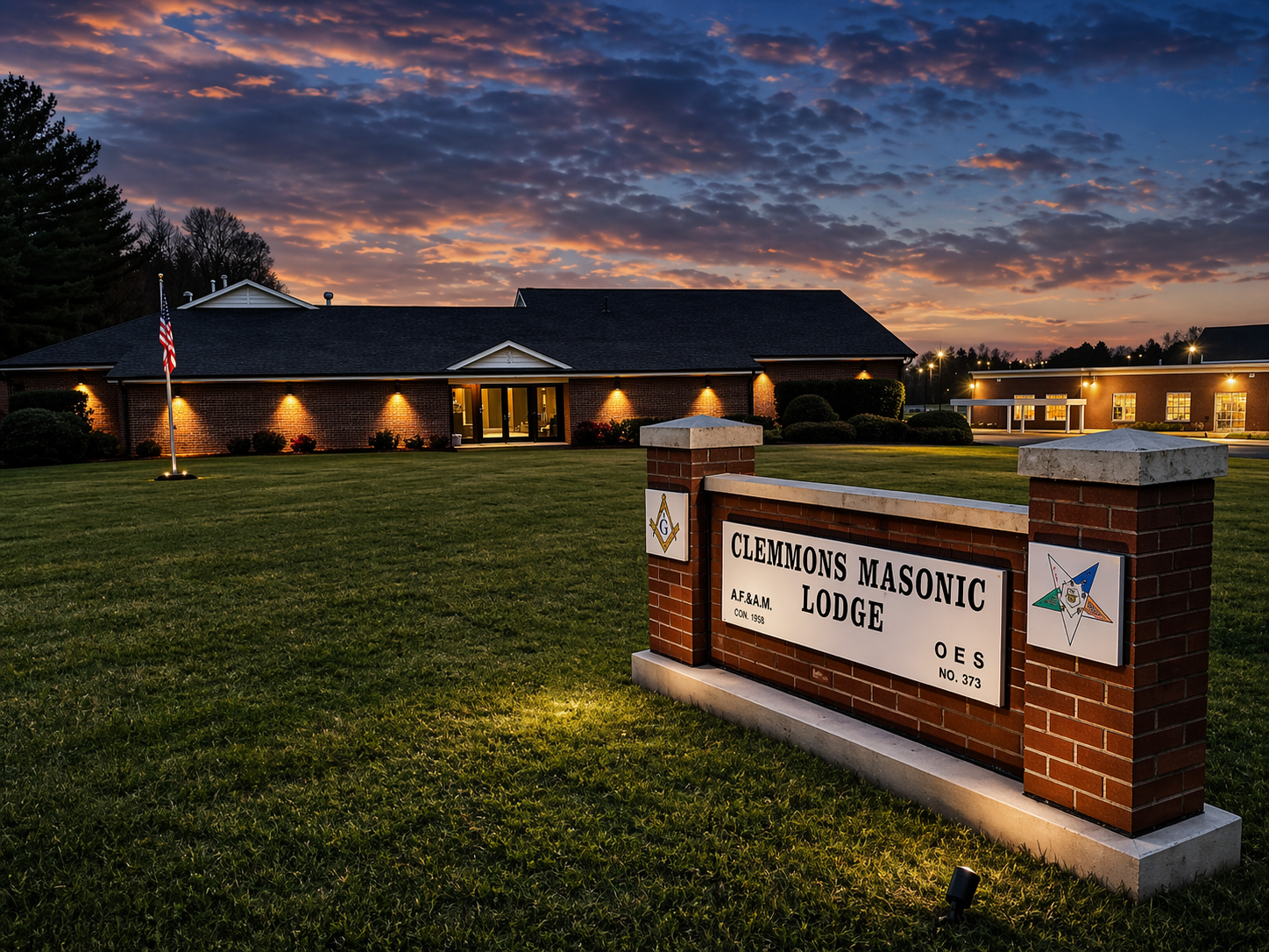 Clemmons Masonic Lodge building at dusk with warm light glowing from arched windows